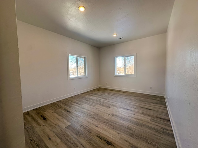 empty room featuring hardwood / wood-style flooring, lofted ceiling, and a textured ceiling