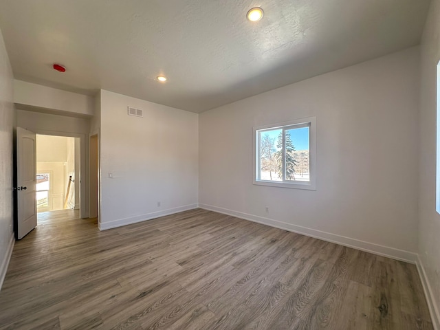 empty room with wood-type flooring and a textured ceiling