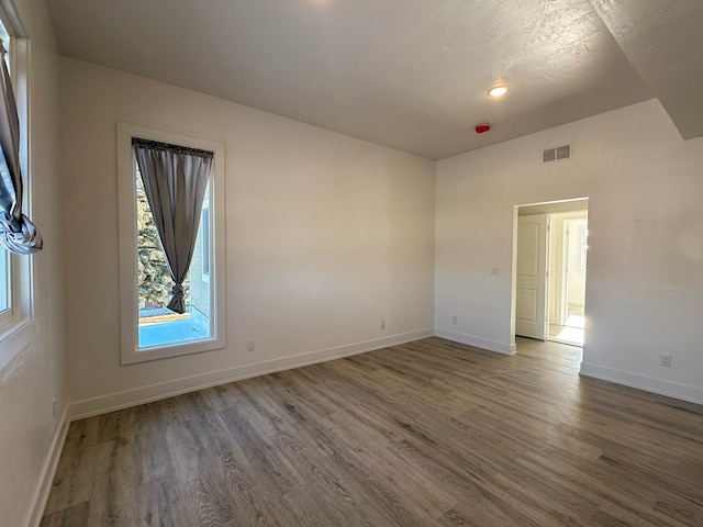 unfurnished room with hardwood / wood-style floors and a textured ceiling