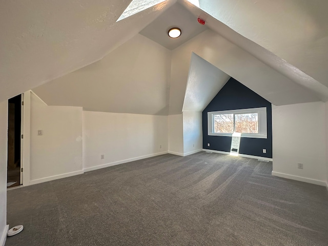 bonus room featuring vaulted ceiling with skylight and dark colored carpet