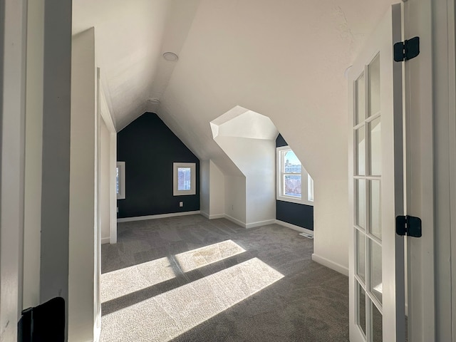 additional living space featuring lofted ceiling and dark carpet