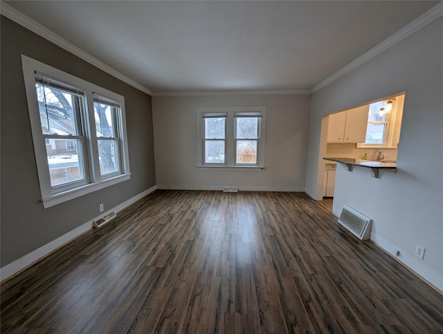 unfurnished living room with sink, crown molding, dark wood-type flooring, and a healthy amount of sunlight