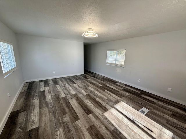 empty room with dark hardwood / wood-style floors and a textured ceiling