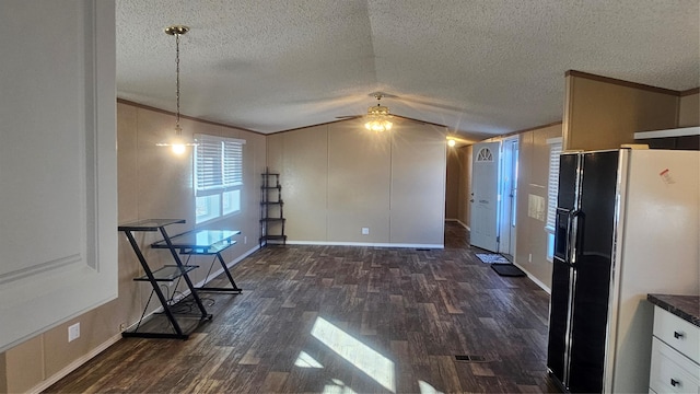 kitchen featuring vaulted ceiling, dark hardwood / wood-style floors, decorative light fixtures, ceiling fan, and black fridge