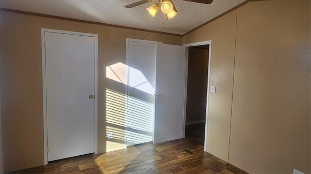 empty room featuring crown molding, vaulted ceiling, a textured ceiling, dark hardwood / wood-style flooring, and ceiling fan