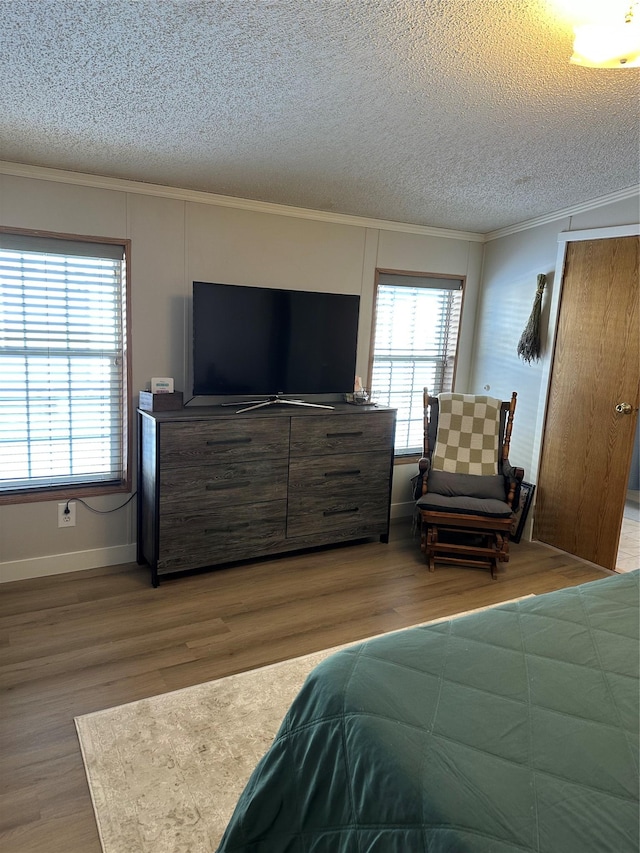 bedroom featuring crown molding, wood-type flooring, and a textured ceiling