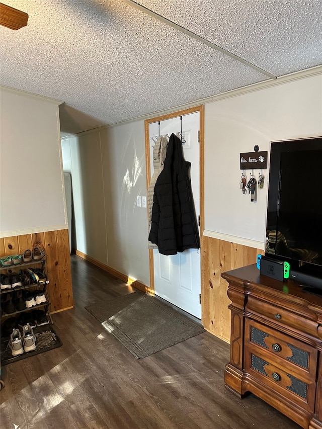 entryway featuring dark wood-type flooring, wooden walls, and a textured ceiling