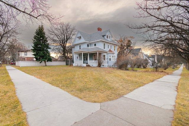 victorian-style house featuring a porch and a yard