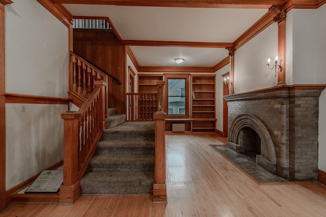 interior space featuring crown molding, built in features, light hardwood / wood-style floors, and a fireplace