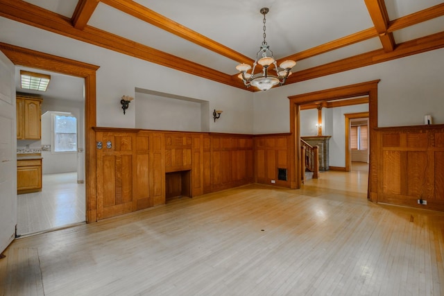 unfurnished room featuring coffered ceiling, a chandelier, ornamental molding, beam ceiling, and light hardwood / wood-style floors