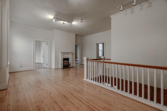 unfurnished living room featuring rail lighting and light hardwood / wood-style flooring