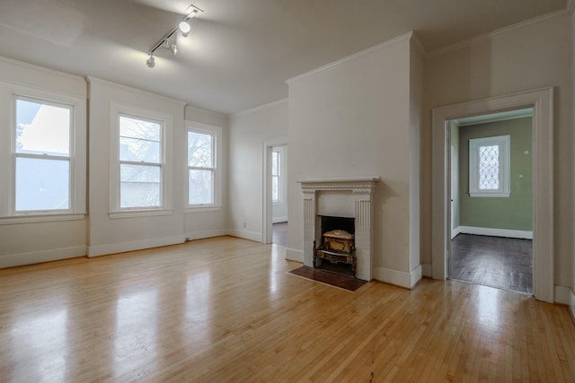 unfurnished living room featuring crown molding, track lighting, and light hardwood / wood-style floors