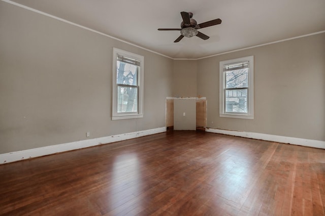 spare room featuring dark wood-type flooring, a wealth of natural light, and ornamental molding