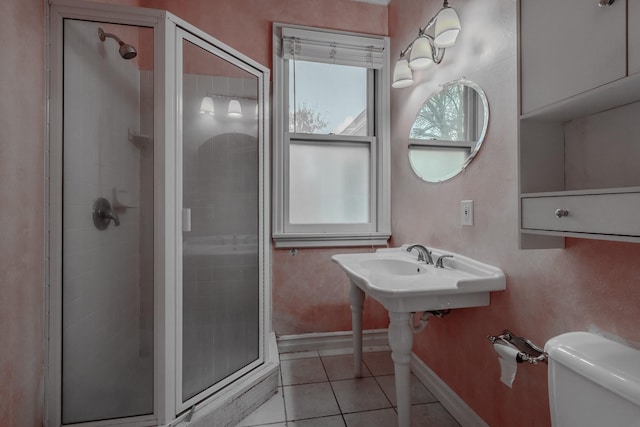 bathroom featuring toilet, a shower with shower door, and tile patterned flooring