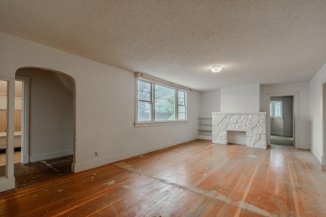 unfurnished living room featuring wood-type flooring, a fireplace, and a textured ceiling