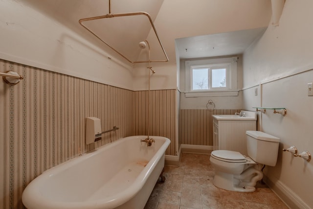 bathroom featuring vanity, a washtub, wooden walls, and toilet