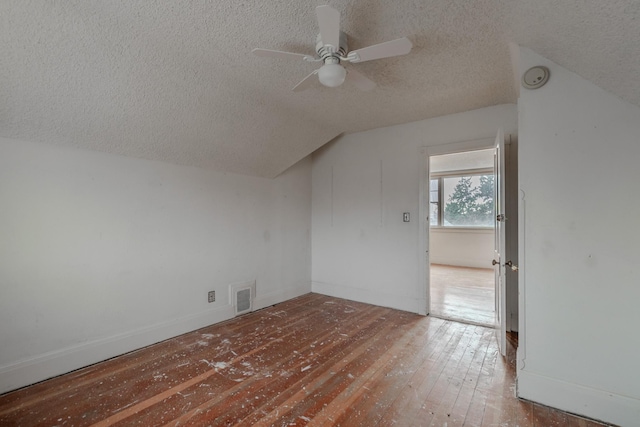 additional living space with vaulted ceiling, hardwood / wood-style floors, ceiling fan, and a textured ceiling