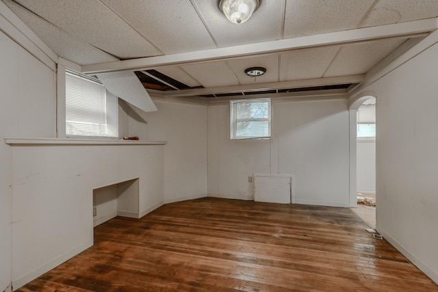 basement with a drop ceiling, hardwood / wood-style floors, and plenty of natural light