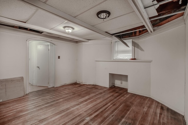 basement featuring a drop ceiling and hardwood / wood-style flooring