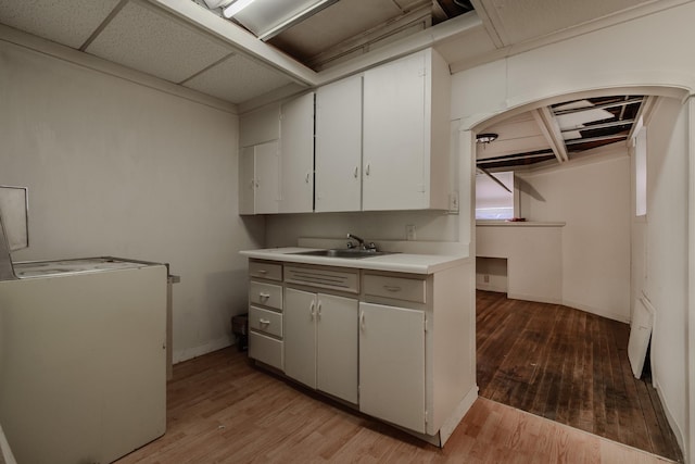 kitchen with sink, light hardwood / wood-style flooring, a paneled ceiling, fridge, and white cabinets