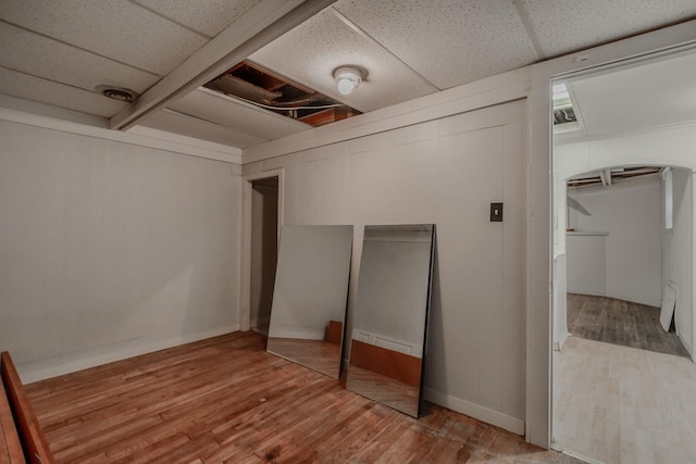 basement featuring wood-type flooring and a drop ceiling