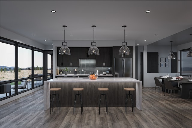 kitchen featuring high end refrigerator, decorative light fixtures, and a large island with sink