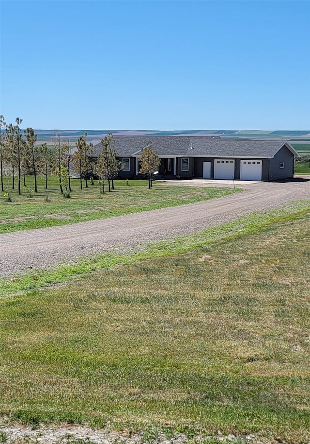 view of front of home featuring a garage, a front yard, and a rural view