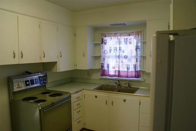 kitchen featuring white cabinetry, sink, stainless steel fridge, and range