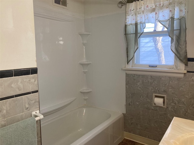 bathroom featuring shower / washtub combination and tile walls