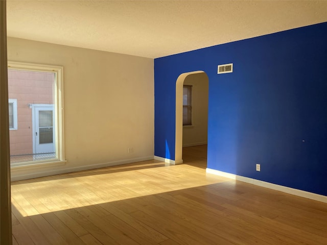 unfurnished room with a textured ceiling and light hardwood / wood-style floors