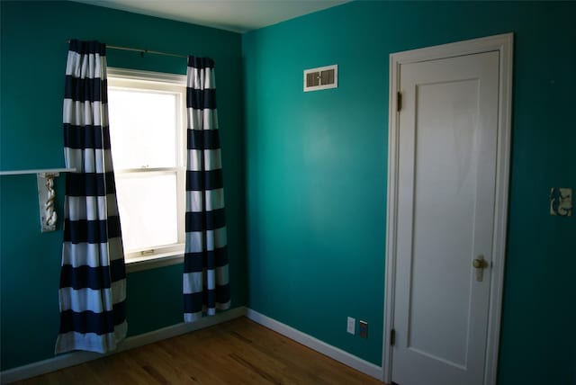 empty room with hardwood / wood-style flooring and plenty of natural light