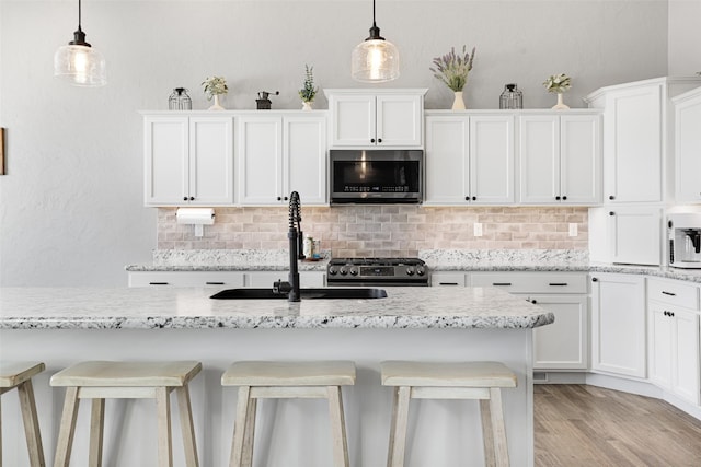 kitchen featuring pendant lighting, white cabinetry, appliances with stainless steel finishes, and a breakfast bar area