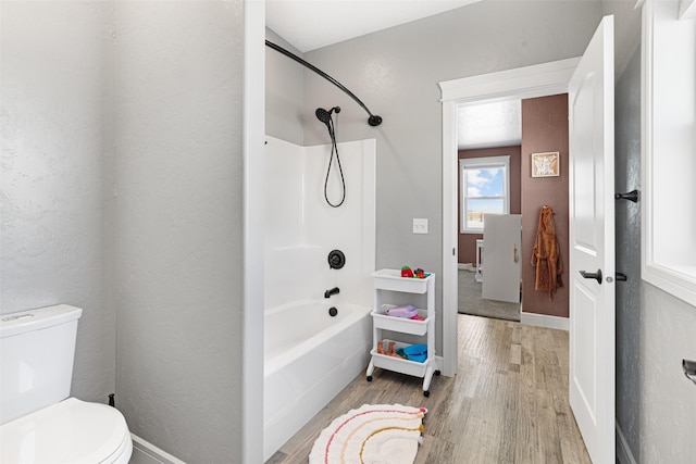 bathroom with shower / bathing tub combination, hardwood / wood-style flooring, and toilet