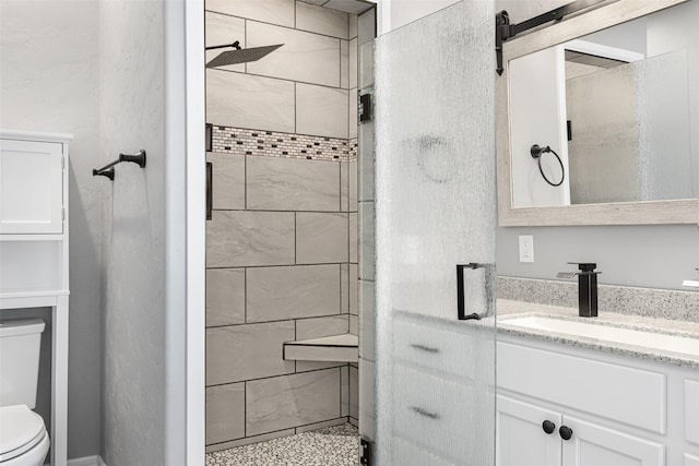 bathroom featuring vanity, a tile shower, and toilet