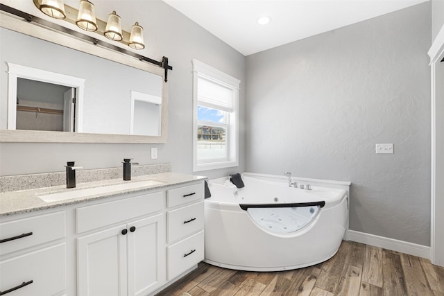 bathroom with hardwood / wood-style flooring, vanity, and a tub