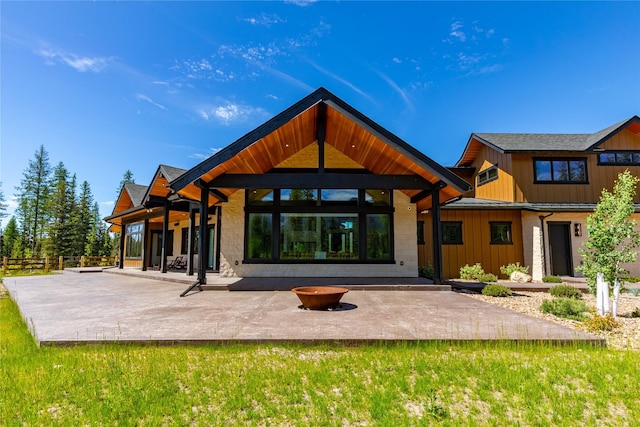 3900 Foothill Rd, Kalispell, MT 59901 - rear view of house with an outdoor fire pit, a patio area, board and batten siding, a standing seam roof, and stone siding