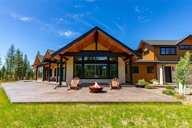 3900 Foothill Rd, Kalispell, MT 59901 - rear view of house with an outdoor fire pit, a patio area, board and batten siding, stone siding, and a standing seam roof