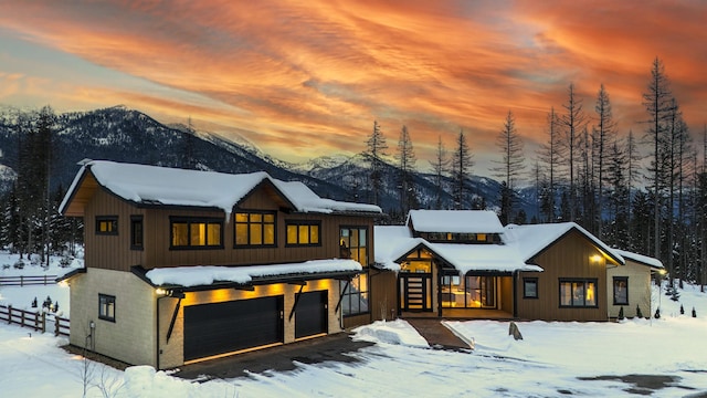 snow covered property featuring a garage and a mountain view