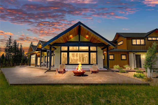3900 Foothill Rd, Kalispell, MT 59901 - back of house at dusk with a fire pit, a patio area, and board and batten siding