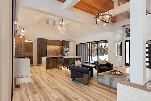 3900 Foothill Rd, Kalispell, MT 59901 - living area featuring a chandelier, beam ceiling, high vaulted ceiling, light wood-style flooring, and baseboards