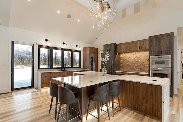 3900 Foothill Rd, Kalispell, MT 59901 - kitchen featuring tasteful backsplash, a sink, high vaulted ceiling, a chandelier, and light wood-type flooring