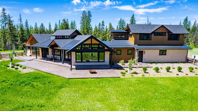 3900 Foothill Rd, Kalispell, MT 59901 - back of house with a standing seam roof, a patio, metal roof, a fire pit, and a lawn