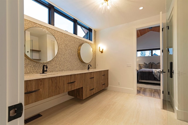 3900 Foothill Rd, Kalispell, MT 59901 - ensuite bathroom featuring wood finished floors, double vanity, decorative backsplash, and baseboards
