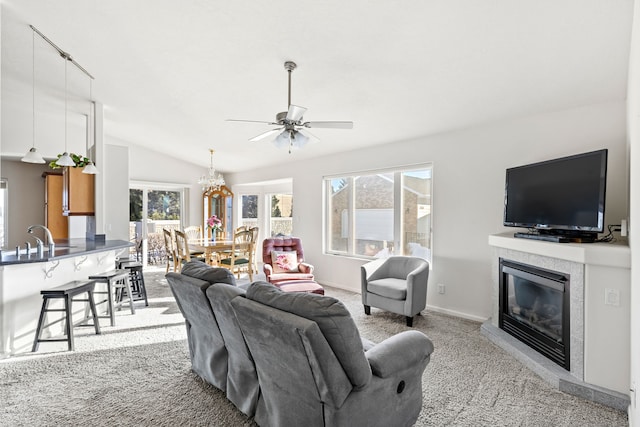 living room featuring sink, ceiling fan, a fireplace, light carpet, and vaulted ceiling