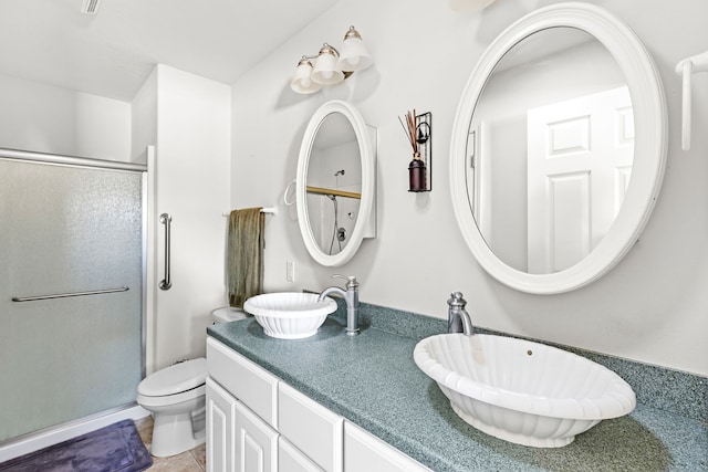 bathroom with tile patterned flooring, vanity, a shower with shower door, and toilet