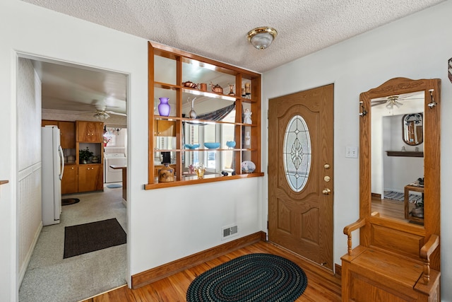 foyer featuring washer / clothes dryer, light hardwood / wood-style flooring, a textured ceiling, and ceiling fan