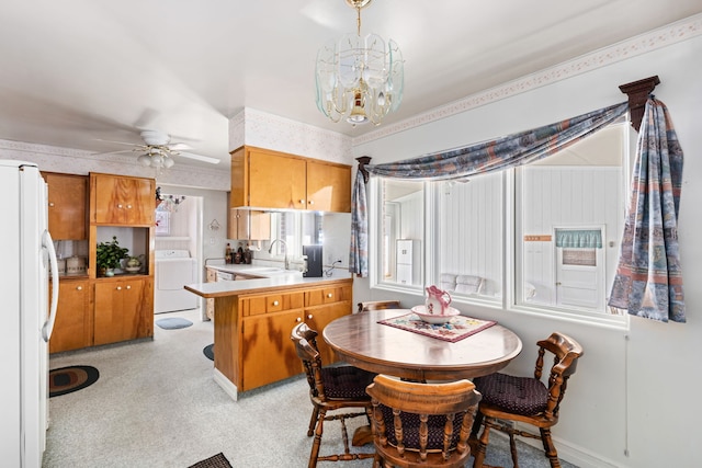 dining area featuring ceiling fan with notable chandelier, washer and dryer, and sink