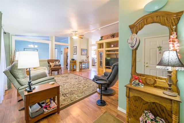 living room with ceiling fan with notable chandelier and light wood-type flooring