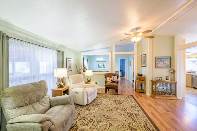 living room with ceiling fan, sink, vaulted ceiling, and light wood-type flooring