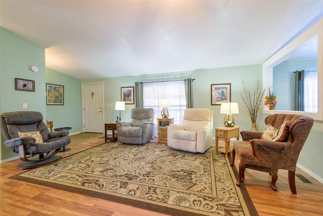 living room featuring wood-type flooring and vaulted ceiling